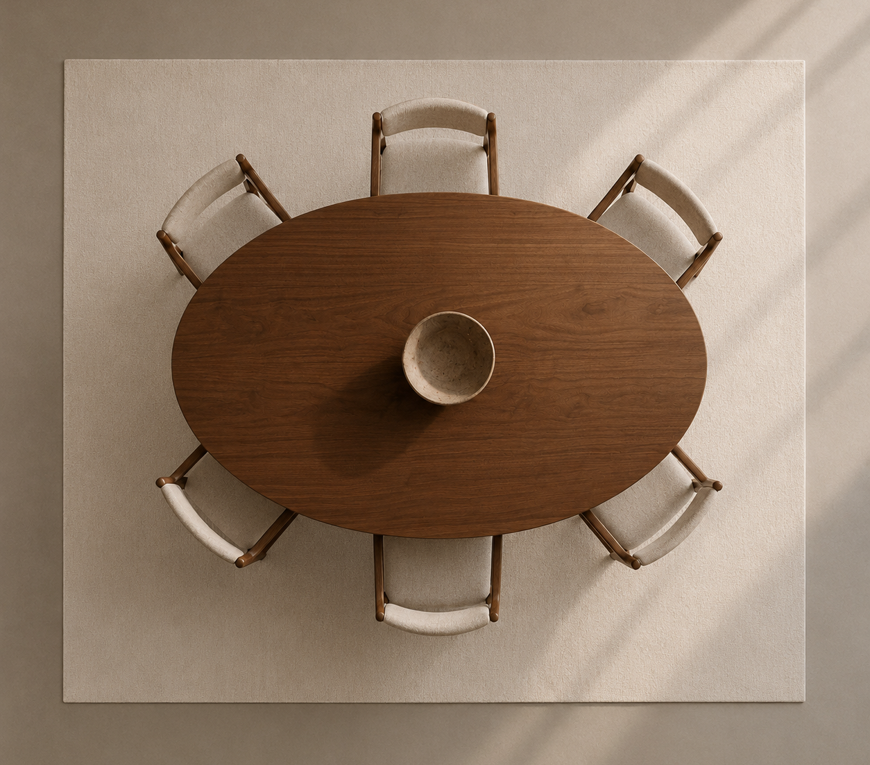 Overhead view of a round wooden dining table surrounded by six upholstered chairs on a large cream rug, with a ceramic bowl centered on the table.