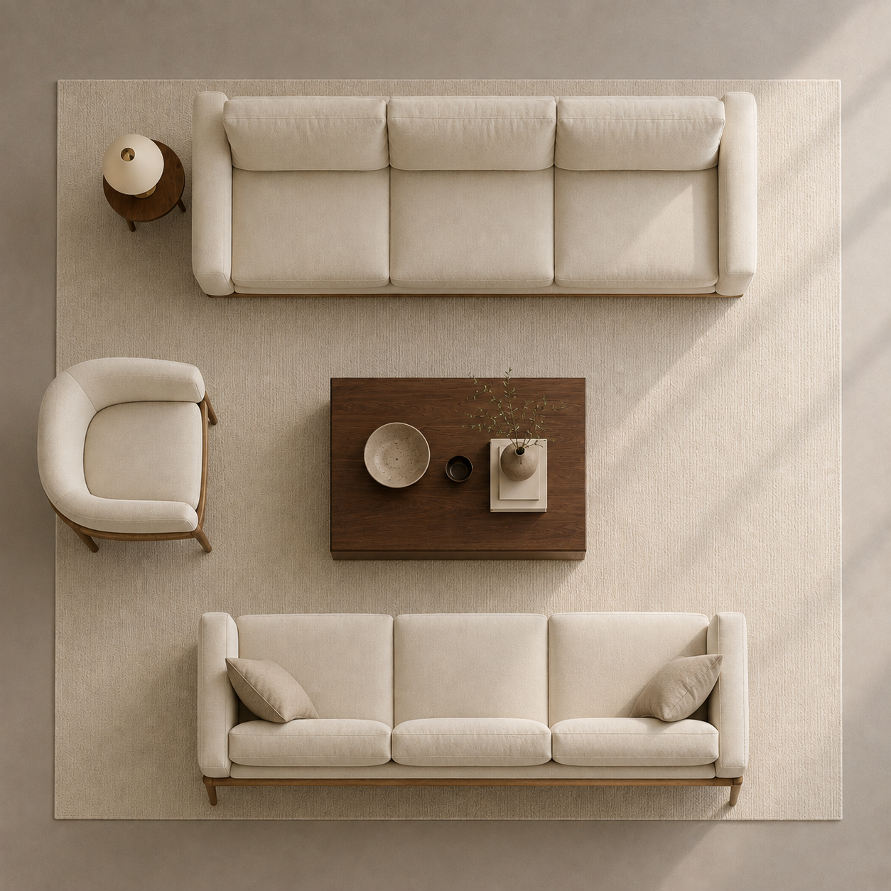Top-down view of a modern living room set featuring two cream-colored three-seater sofas, one matching armchair, a dark wood coffee table, and a round side table on a large textured beige rug.