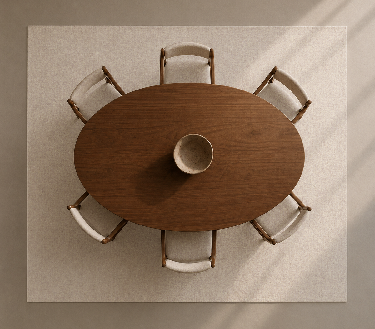 Overhead view of a round wooden dining table surrounded by six upholstered chairs on a large cream rug, with a ceramic bowl centered on the table.